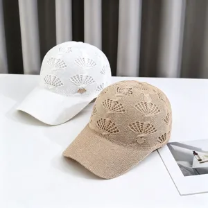 Detailed view of hollow knit baseball caps in white and khaki with rhinestone heart charms.