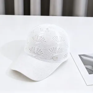 White knitted hollow baseball cap detail, featuring floral crown pattern and rhinestone heart charm.
