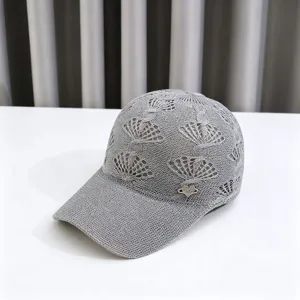 Detail shot of a grey knit hollow out baseball cap with shell pattern and rhinestone heart logo.