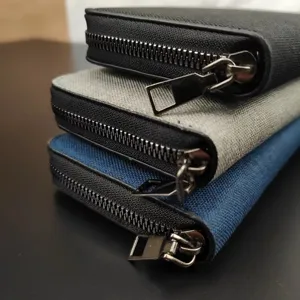 Primo piano di portafogli lunghi in tela con zip in nero, grigio e blu multitasche.