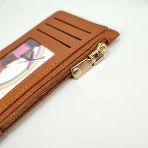 Close-up detail of slim brown leather card holder with zipper pocket and clear slot.
