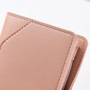 Close-up detail shot of women pink leather wallet showing texture, stitching and zipper.