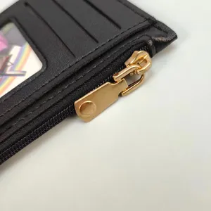 Close up view of black leather card holder with gold zipper, showing detailed stitching and slots.