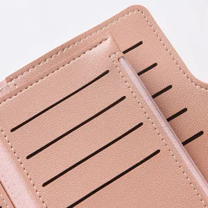 Close-up detail of women's pink leather wallet card slots with neat white stitching.