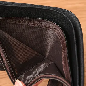 Nahaufnahme des Inneren der schwarzen Herrenbörse mit braunem Futter und Reißverschluss.