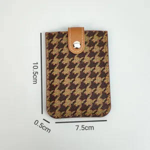 Detailed view of houndstooth card holder with brown leather snap closure and compact size design.