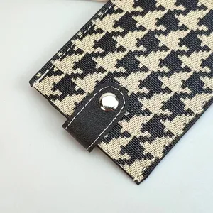Close-up detail of the classic houndstooth card holder with snap leather pull tab.
