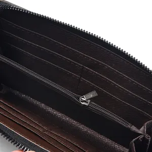 Dettaglio portafoglio uomo lungo con zip, porta carte in pelle marrone e monete.