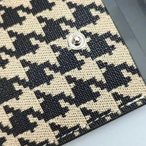 Close-up detail of houndstooth card holder featuring metal snap button and neat stitching.