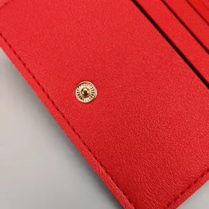 Roter Kartenhalter Nahaufnahme mit feinen Nähten, goldenem Druckknopf und Steckplätzen.