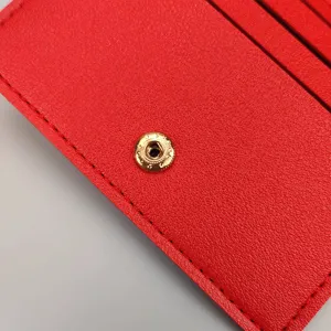 Detailansicht des roten Lederkartenetuis mit Druckknopf, mehreren Fächern und feiner Naht.