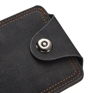 Gros plan détaillé d'un portefeuille homme en cuir noir avec surpiqûres oranges et bouton.