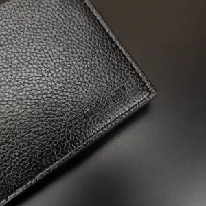 Gros plan sur la texture d'un portefeuille pour homme en cuir noir avec logo gaufré.