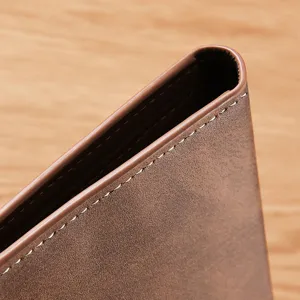 Gros plan sur le bord du portefeuille en cuir marron avec des coutures blanches.