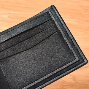 Nahaufnahme der Kartenfächer eines schwarzen Ledergeldbörses mit feiner Nahtstruktur.