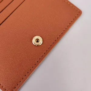 Braunes Leder Kartenetui Detail Nahaufnahme mit feinen Nähten und goldenem Druckknopf.