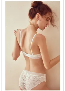 Gedetailleerd uitzicht op de elegante witte kanten lingerieset tegen een neutrale wand.