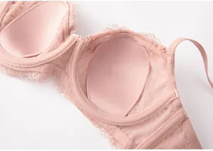 Close-up detail view of a pink lace French bra interior, showing cups and adjustable straps.