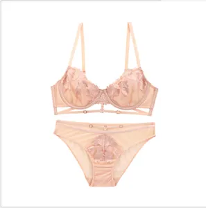 Vista detallada del delicado bordado de hojas y anillos en lencería rosa sexy.