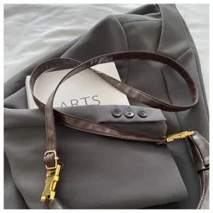 Detail view of a stylish vintage leather messenger bag strap with gold hardware.