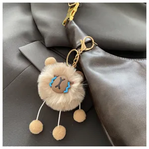 Detail shot of a vintage brown dumpling shoulder bag with a cute fluffy plush animal pendant.