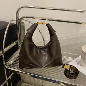 Detailed view of stylish dark brown hobo shoulder bag featuring gold-tone hardware.