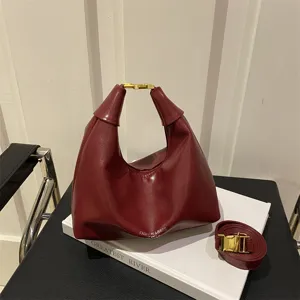Stylish retro hobo dumpling shoulder bag in burgundy leather with chic metallic buckle.