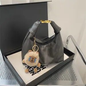 Black PU leather hobo shoulder bag with metal buckle and cute plush bear keychain charm.