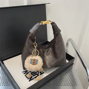 Brown hobo dumpling bag with gold buckle handle and cute plush charm for women commute