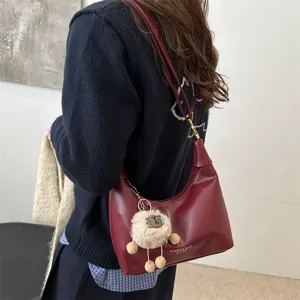 Detail shot of dark red leather hobo bag with cute plush sheep charm, showcasing daily wear.
