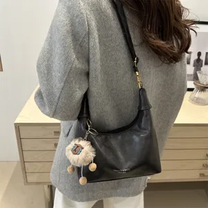 Detail view of the black faux leather hobo dumpling shoulder bag with cute fluffy animal charm.
