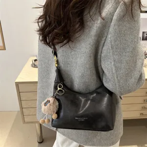 Stylish black leather shoulder bag with plush charm, perfect for daily commuting.