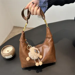 Fashionable brown retro hobo shoulder bag with cute plush pendant for daily commute and casual use.