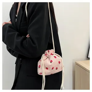 Detail view of a cute pink corduroy strawberry bucket bag with white drawstring straps.