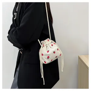 Detail view of the cute corduroy bucket bag featuring sweet red strawberry prints and straps.