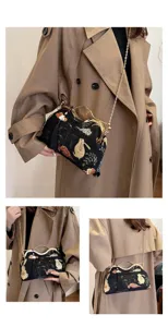 Chinese vintage style embroidered crossbody bag with metal frame and chain strap, elegant detail.