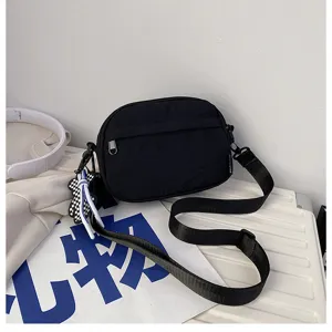 Gros plan détaillé du sac bandoulière décontracté noir avec tissu résistant et poche zippée.