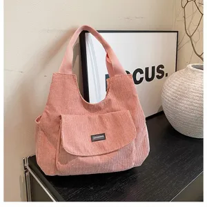 Pink corduroy tote bag detail showing texture, front pocket and sturdy handle in a chic setup.