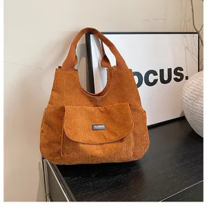 Brown corduroy tote bag detail, casual commuter shoulder bag with front pocket design.