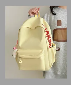 Detailed view of the yellow canvas casual school backpack featuring side red letter print and charm.