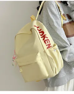 Casual canvas backpack with stylish red lettering, front pocket, and cute pendant detail.