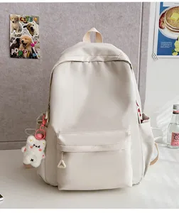 Detail shot of minimalist beige casual student backpack with cute plush bear keychain accessory.
