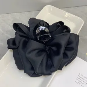 Close up detail of black satin flower hair claw clip showing exquisite fabric texture