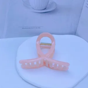 Detail view of a sweet pink acrylic hair claw clip, elegant medium size hair accessory.
