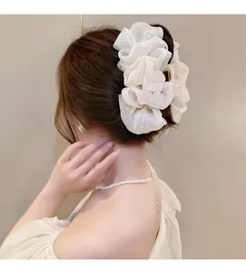 Vue détaillée d'une pince à cheveux en organza blanc avec strass scintillants.