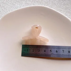 Close-up of a pink translucent mini hair claw clip with a ruler for size detail view.