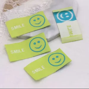 Close-up of colorful woven smiley face fabric labels with text, ideal for DIY handmade hair accessories.