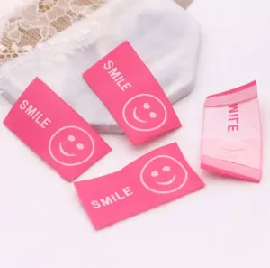 Close-up detail of pink woven smiley face fabric labels, perfect for DIY hair accessories.