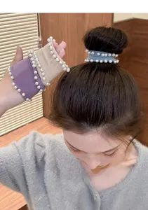 Detailed view of the elegant pearl hair tie worn on bun and wrist, elastic fabric design.