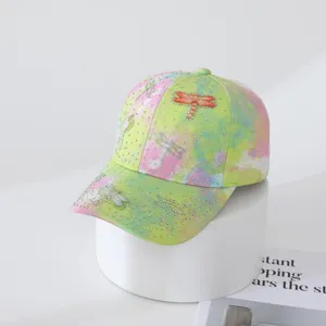 Rhinestone dragonfly detail on tie-dye baseball cap close up view showing texture and craftsmanship.
